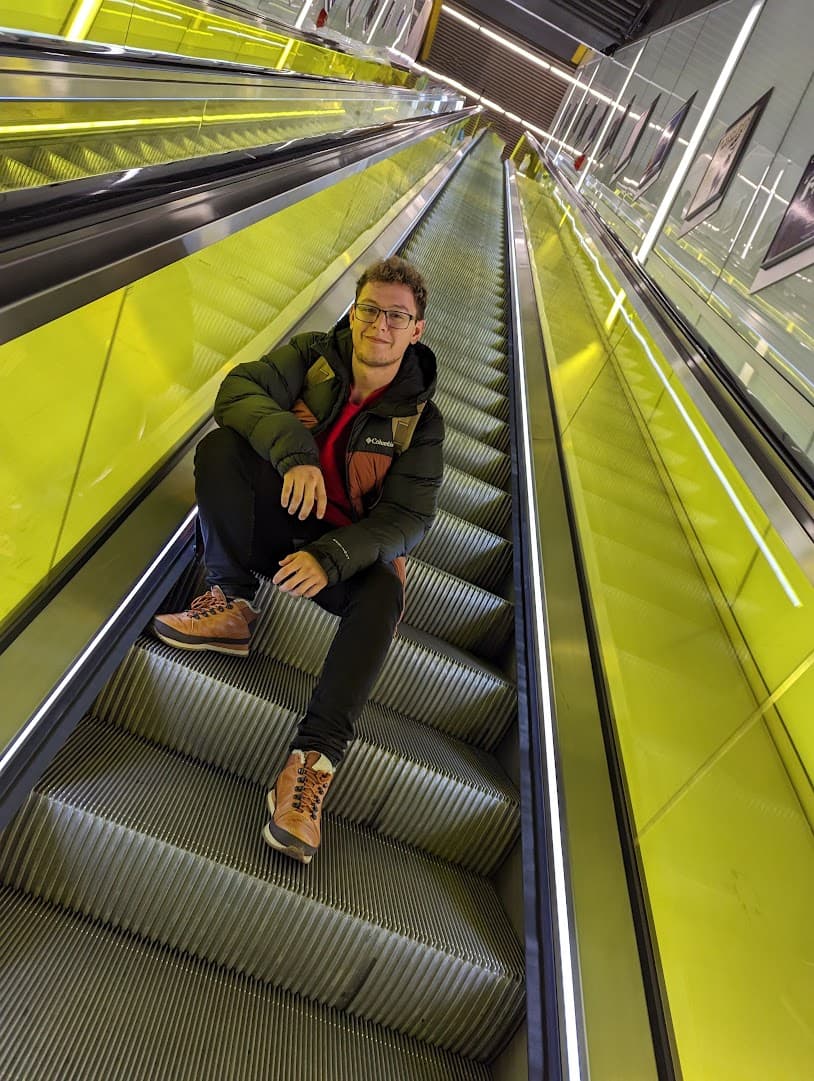 Eray sitting on an escalator